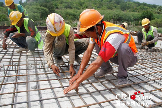 中国和东帝汶工人在苏艾高速公路施工现场一起完成工作